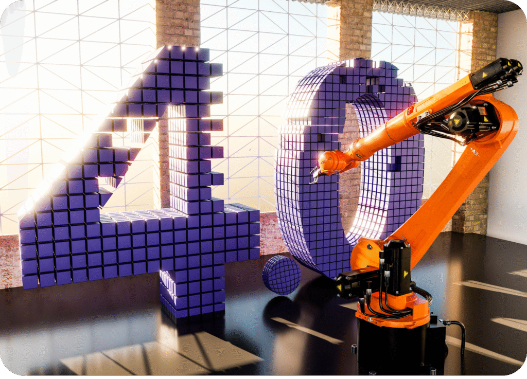 Imagem 3D interna de fábrica com luz intensa, mostrando um grande braço robótico industrial laranja ao lado da representação do número '40' construído com pequenos cubos digitais roxos.
